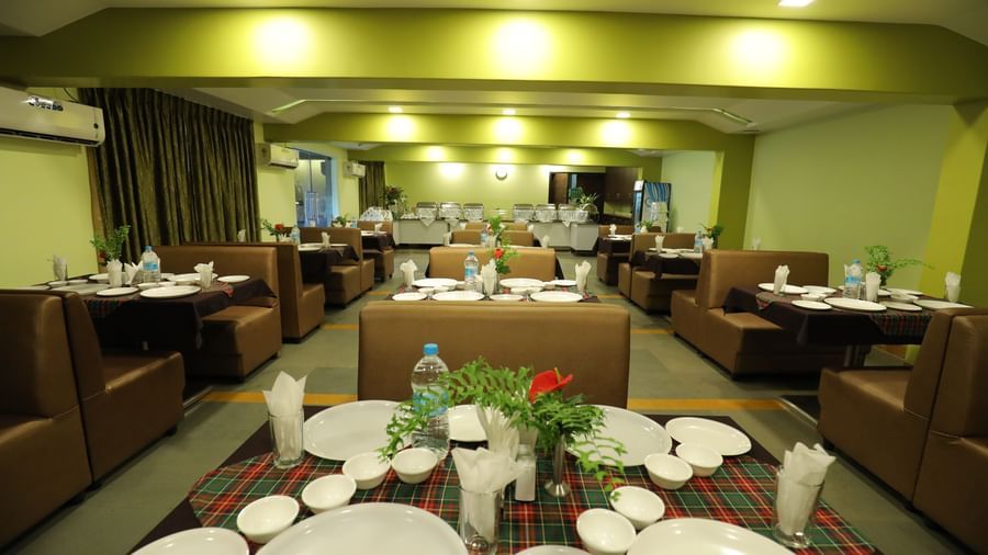 Close-up of tables set with plates and bottles on a carpeted floor at Krushnai Resort.