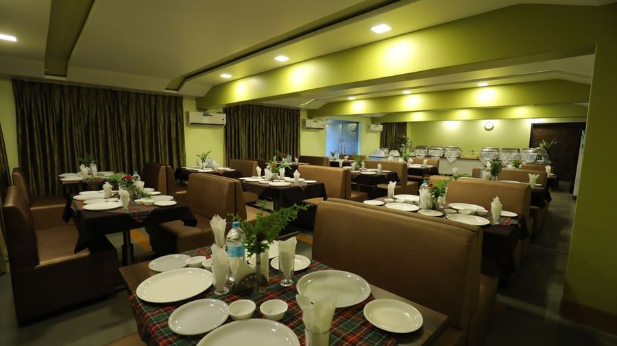 Dining area with neatly arranged tables and chairs at Krushnai Resort, with plates and cutlery placed.