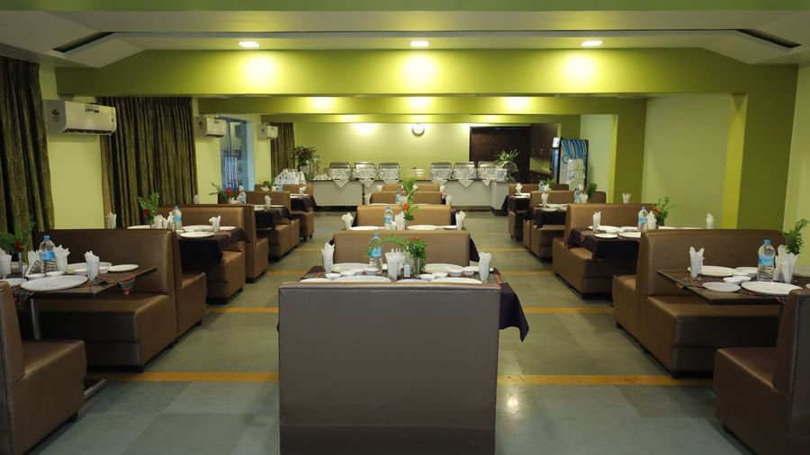 Multiple dining tables arranged in rows at Krushnai Resort restaurant.
