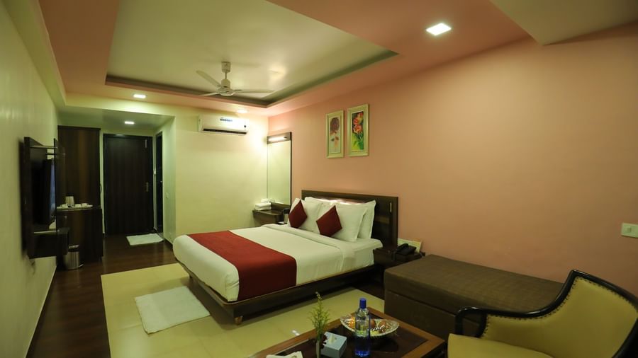 A spacious bedroom at Krushnai Resort with lounge chairs, coffee table, and a well made double bed.