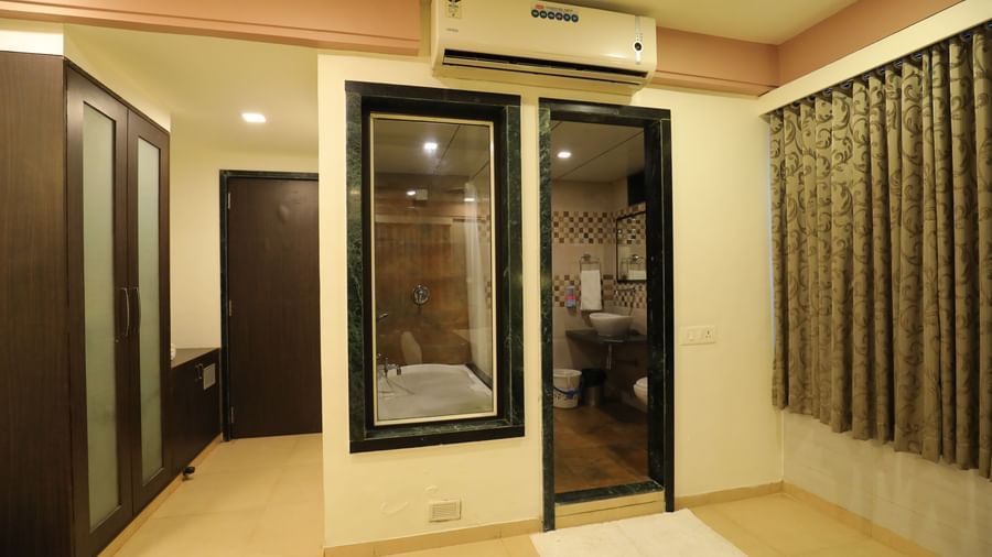 The entrance area to a Krushnai Resort room, showing a wardrobe and a glass panelled wall with a view of the washroom.