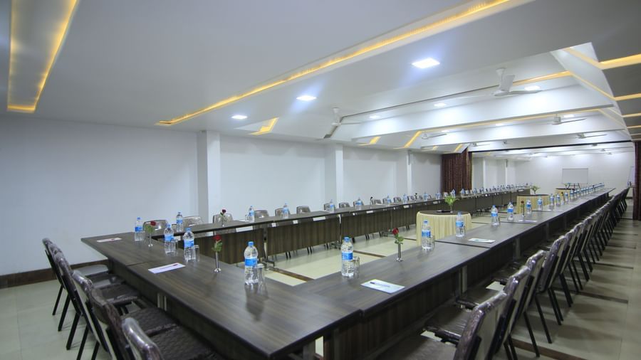 A bright event space at Krushnai Resort with chairs and a central table set for a meeting.