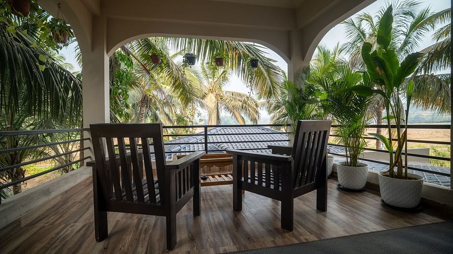 Tropical balcony setup with wooden seating and lush coconut trees view at Kssemya.