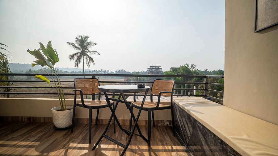 A balcony with minimalist furniture overlooking lush greenery and palm trees at Kssemya.