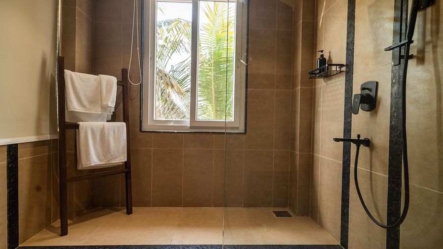 Spacious walk-in shower with large window, wooden towel stand, and sleek design at Kssemya.
