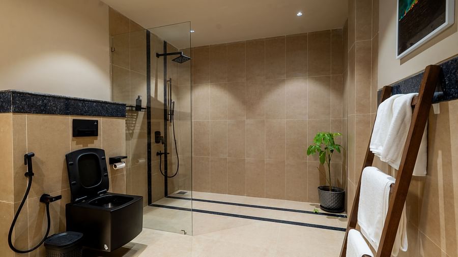 Modern bathroom with walk-in shower, black fittings, and towel racks at Kssemya.