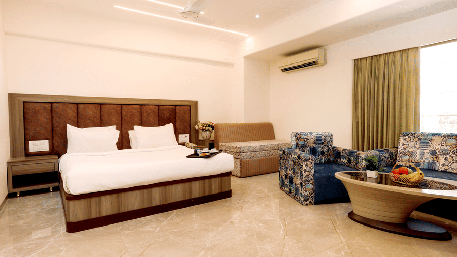 Full view of a bright and airy suite showing a bed, sofa seating area, coffee table, and air conditioning unit at Kumar Resort by Turtle.