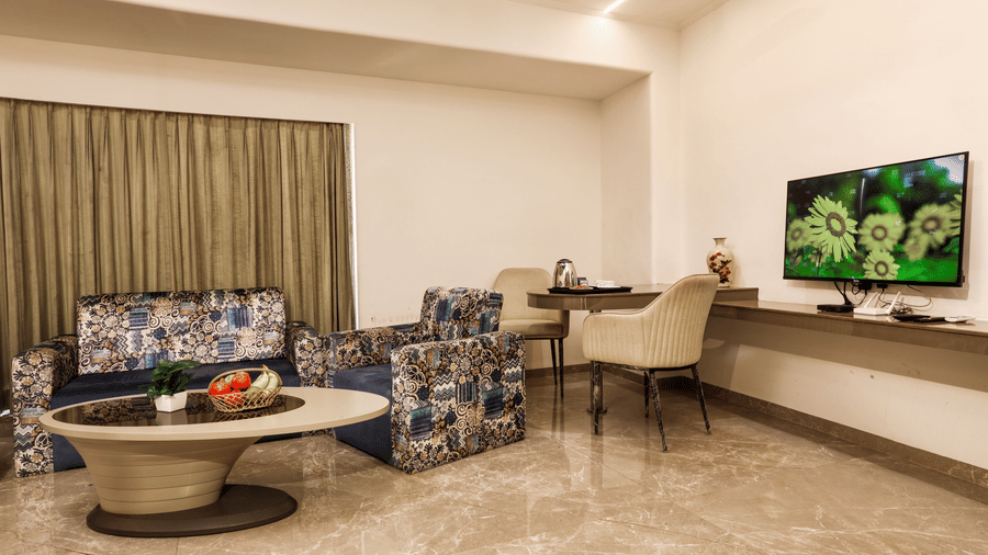 Spacious suite living area showing comfortable patterned sofa seating, a central coffee table, and a desk/workstation at Kumar Resort by Turtle.