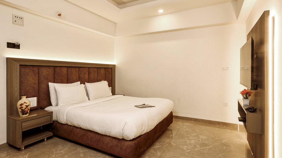 Room with a padded headboard, crisp bedding, and bright overhead lighting at Kumar Resort by Turtle.