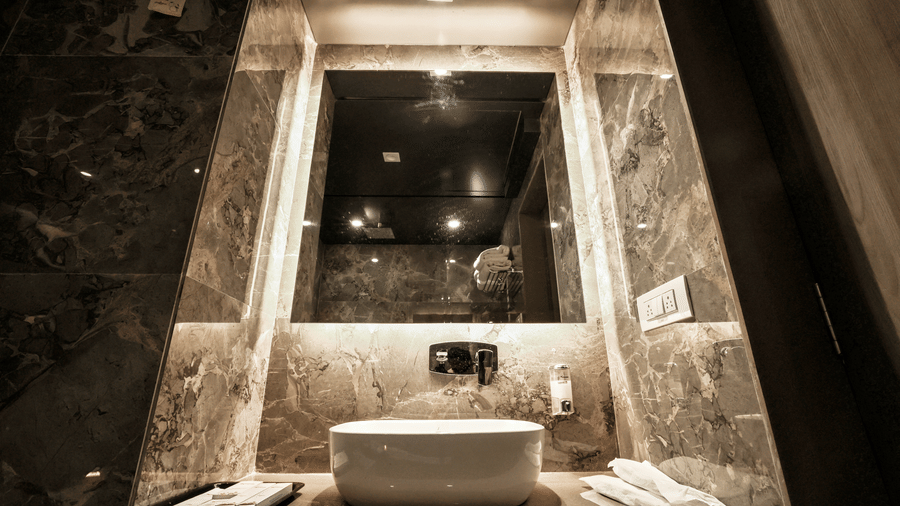 Close-up of a contemporary bathroom vanity featuring a sink, a large back-lit mirror, and premium wall finishes at Kumar Resort by Turtle.