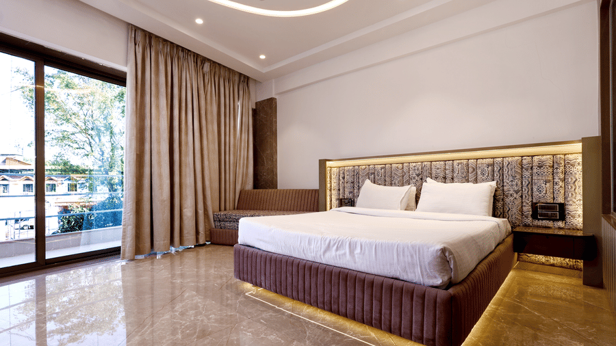 Spacious room with a double bed, floor-to-ceiling glass sliding doors leading to an outdoor area, and decorative ceiling lighting at Kumar Resort by Turtle.