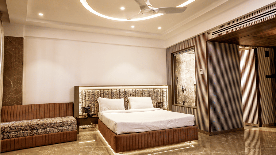Wide view of a large suite featuring a bed, comfortable seating, and elegant ceiling design at Kumar Resort by Turtle.