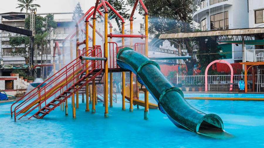 A water playground area featuring several slides and climbing structures next to the swimming pool at Kumar Resort by Turtle.