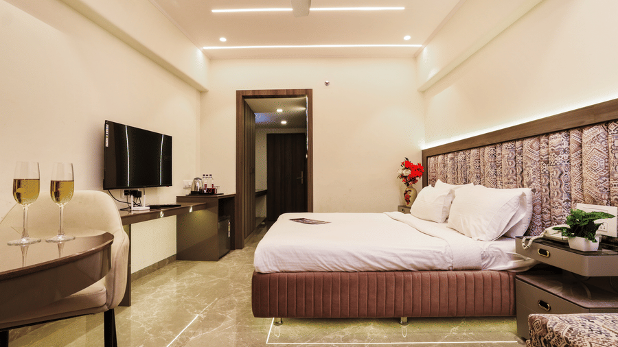 Bedroom with a television, seating area, and a bed at Kumar Resort by Turtle.