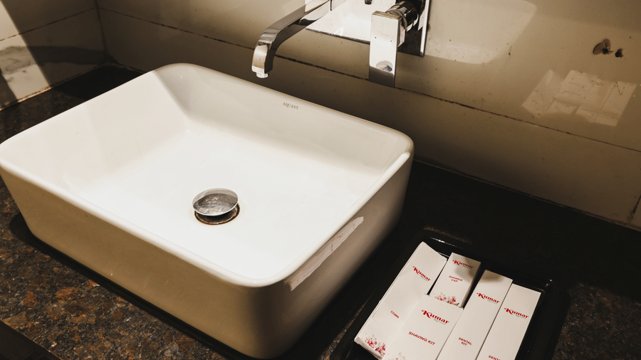 Close-up of a washbasin with toiletries arranged beside it at Kumar Resort by Turtle.