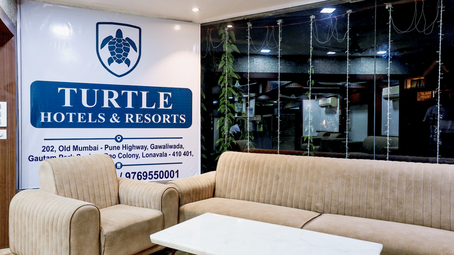 View of a common seating area with contemporary sofas, a coffee table, and the resort's official branding signage at Kumar Resort by Turtle.