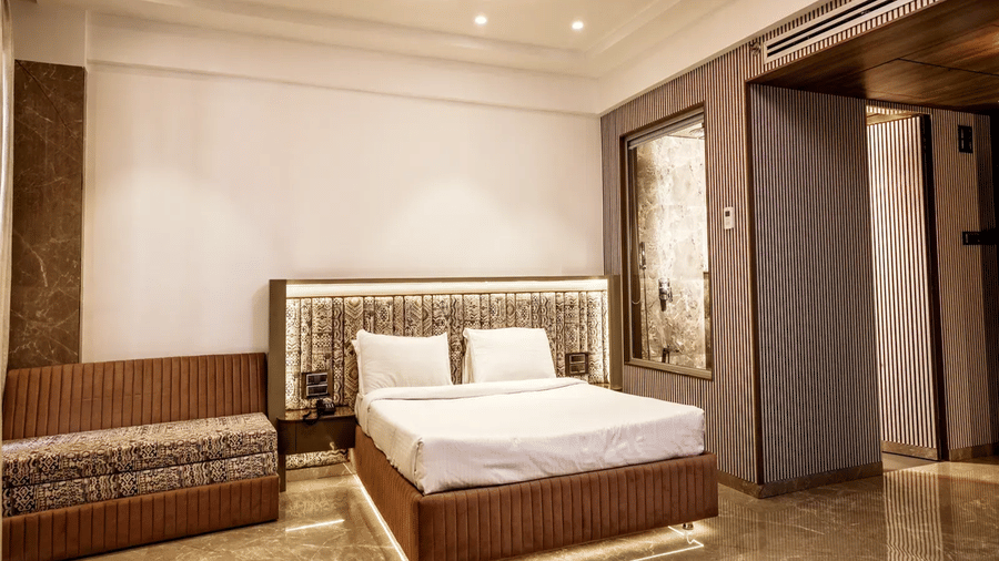 Suite at Kumar Resort by Turtle with king bed, patterned headboard, brown velvet base, upholstered bench and a circular cove-lit ceiling with fan.