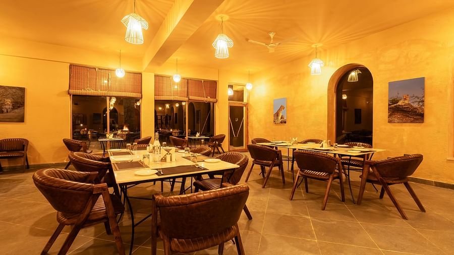 An image of L cave restaurant featuring ceiling lights, dining table and chairs in boho theme and there is also an open entrance - Kurja Jawai
