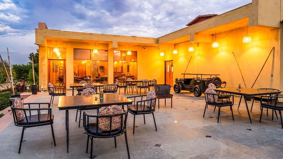 An image of rosettes restaurant featuring several lamps hanging from the roof and various sets of  tables and chairs are placed both indoor and outdoor at Kurja Jawai