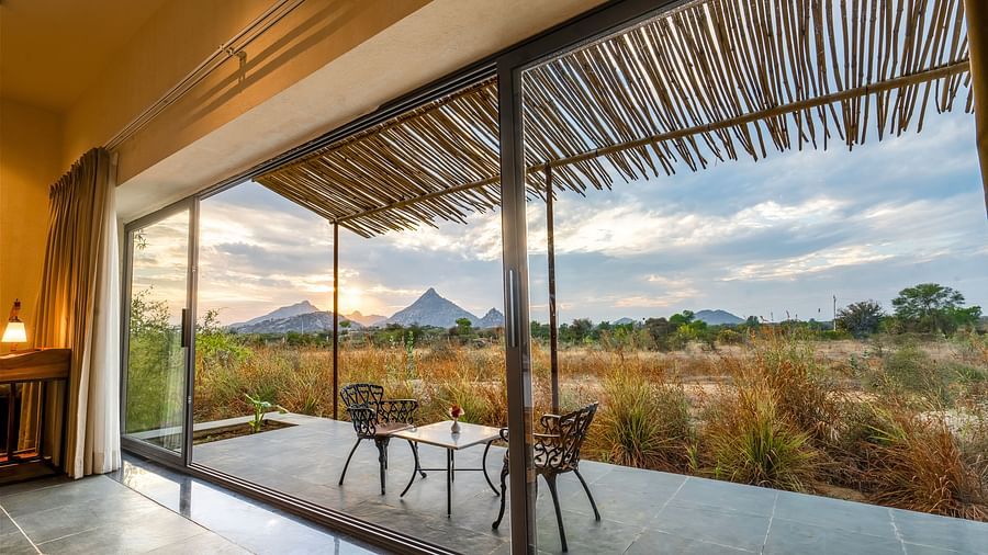 An image of a courtyard of Stone Cottages featuring two chairs and a centre table from where a beautiful scenery can be enjoyed at Kurja Jawai