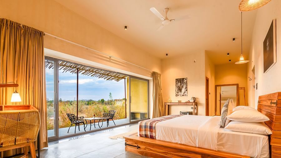 An image of bedroom at Kurja Jawai featuring a double size bed, a work desk and chair, a table with tea and coffee maker, and a coutryard with seating area 