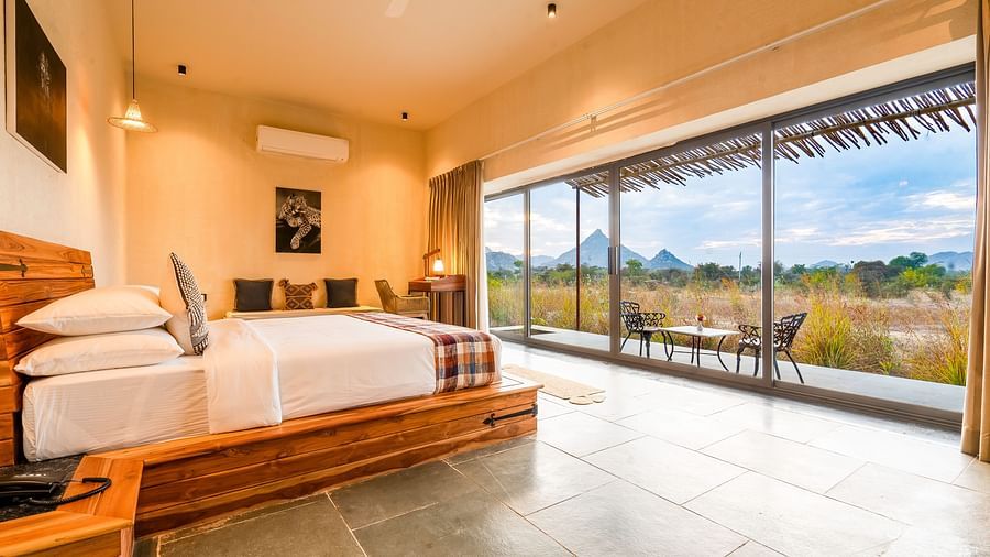 An image of a bedroom facing towards the glass door from where outdoor scenery can be enjoyed - Kurja Jawai