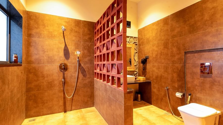 An image of a washroom divided by a partition featuring a shower head and jet spray and the other side has mirror, sink, faucet, etc. at Kurja Jawai