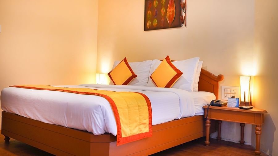 a view of a plush bed with yellow and orange cover and pillows at La Montana By TGI, Ooty