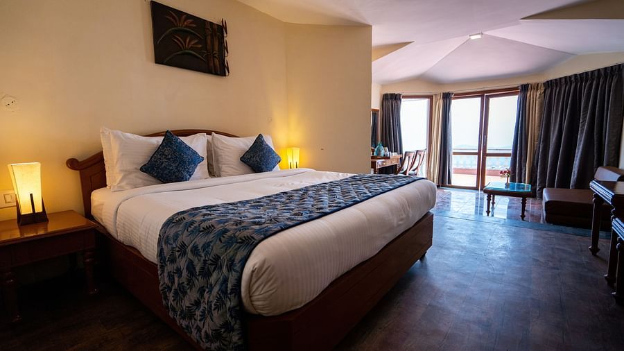 comfy bed with blue duvet and pillows at La Montana By TGI, Ooty