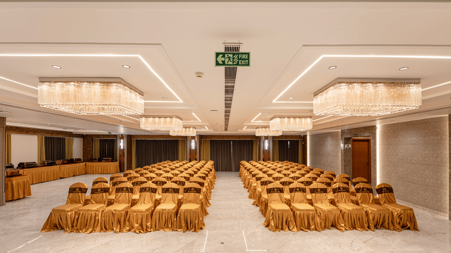 Banquet hall setup with golden chairs and chandeliers at Lemonridge Hotels, IDPL Balanagar.