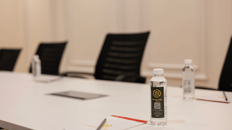 Close-up of boardroom table with bottled water and notepads at Lemonridge Hotels, IDPL Balanagar.