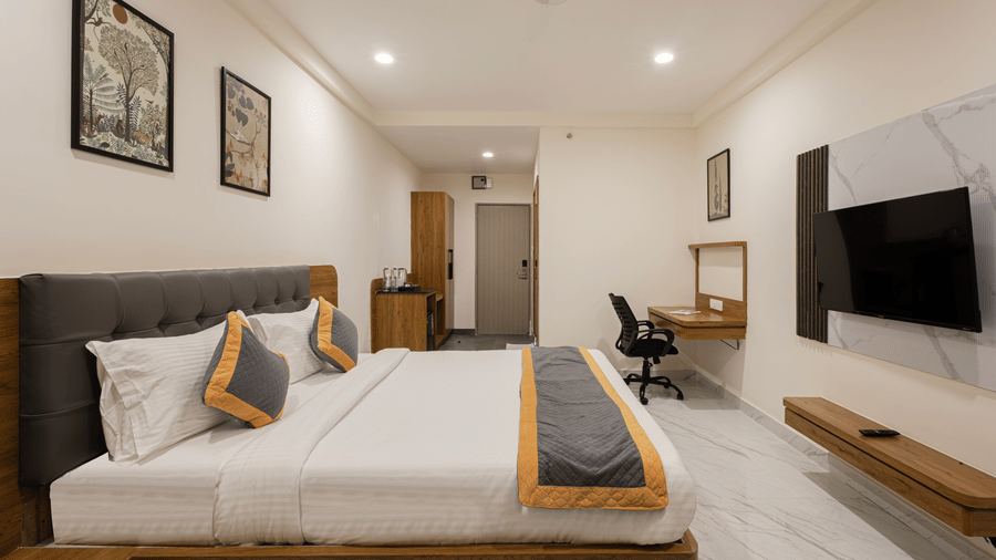 Elegant room with wall-mounted TV, work desk, and twin bedding at Lemonridge Hotels, IDPL Balanagar.