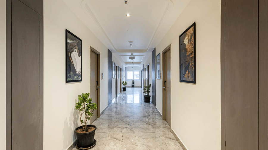 Bright corridor with marble flooring and framed artwork at Lemonridge Hotels, IDPL Balanagar.