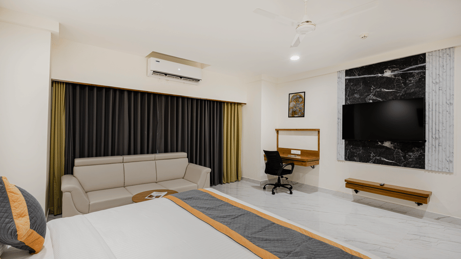 Interior view of bedroom featuring work desk and window curtains at Lemonridge Hotels, IDPL Balanagar.