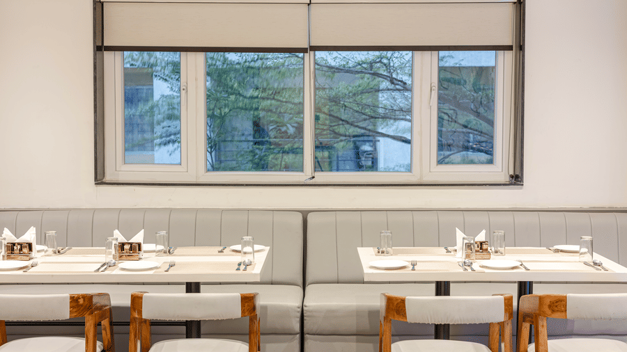 Window-side dining tables in the in-house restaurant at Lemonridge Hotels, IDPL Balanagar