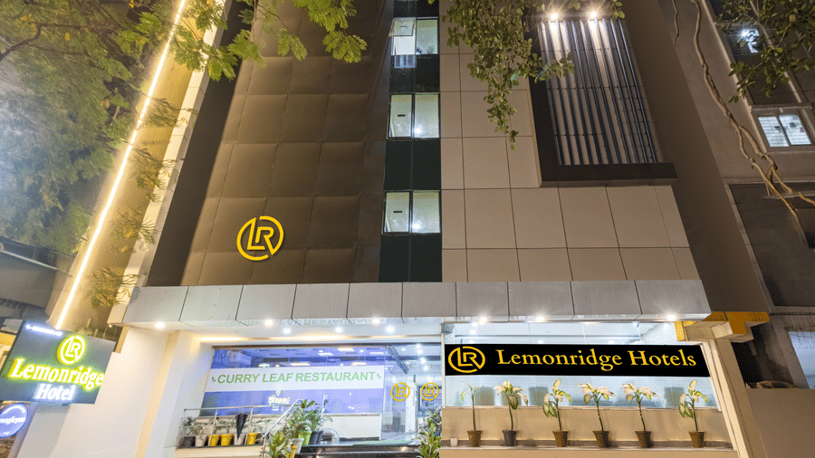 The exterior front entrance of Lemonridge by Monday Hotels - Kukatpally is lit up at night, showing steps, logos, and a lit main sign.