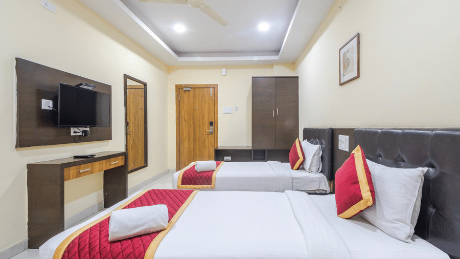 Comfort room with 2 cosy beds, mirror, ceiling fan, wardrobe, and wall-mounted TV at Lemonridge by Monday Hotels - Kukatpally.