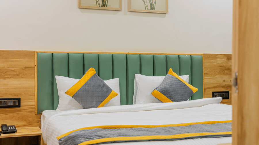 A bedroom at Lemonridge by Monday Hotels - KPHB featuring a large bed, matching runners, green headboard, and bedside nightstand.