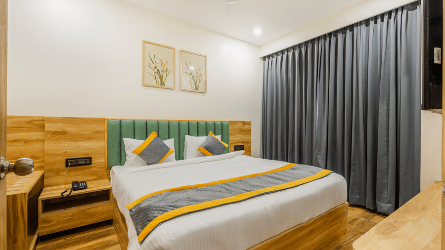 A bedroom at Lemonridge by Monday Hotels - KPHB featuring a large bed, green headboard, floral pictures, study desk, and cabinet.