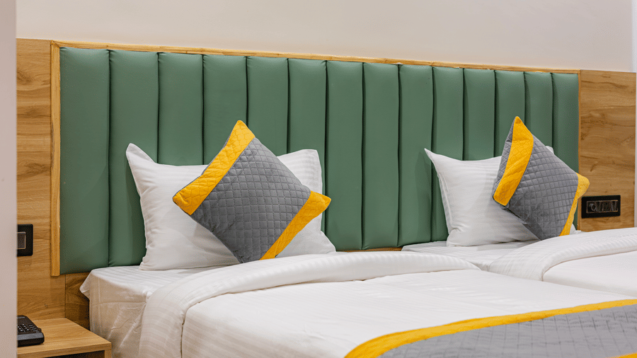 A bedroom at Lemonridge by Monday Hotels - KPHB featuring a large bed, matching runners, green headboard, and wood-paneled walls.