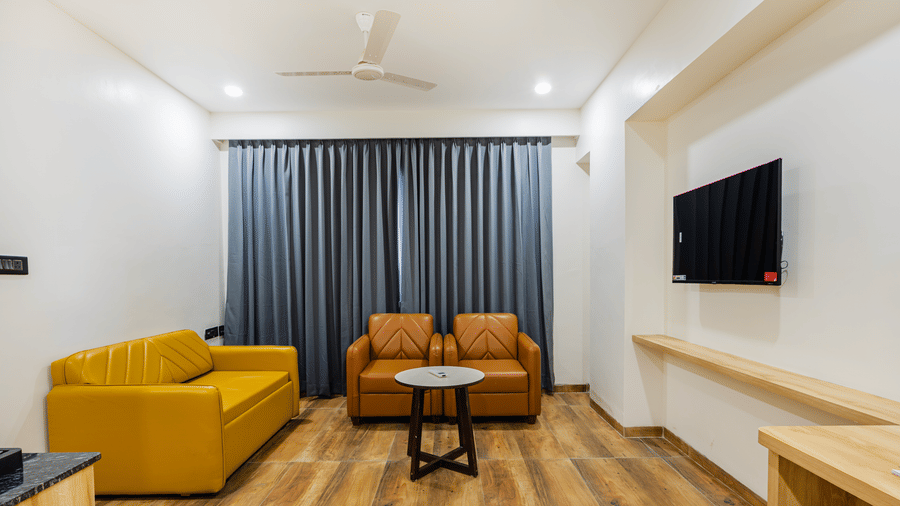 A suite living area at Lemonridge by Monday Hotels - KPHB featuring a yellow sofa, 2 armchairs, coffee table, and console table.