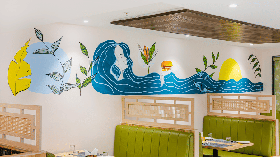 Curry Leaf restaurant at Lemonridge by Monday Hotels - KPHB featuring a close-up wave wall painting, green booths, and overhead wood paneling.