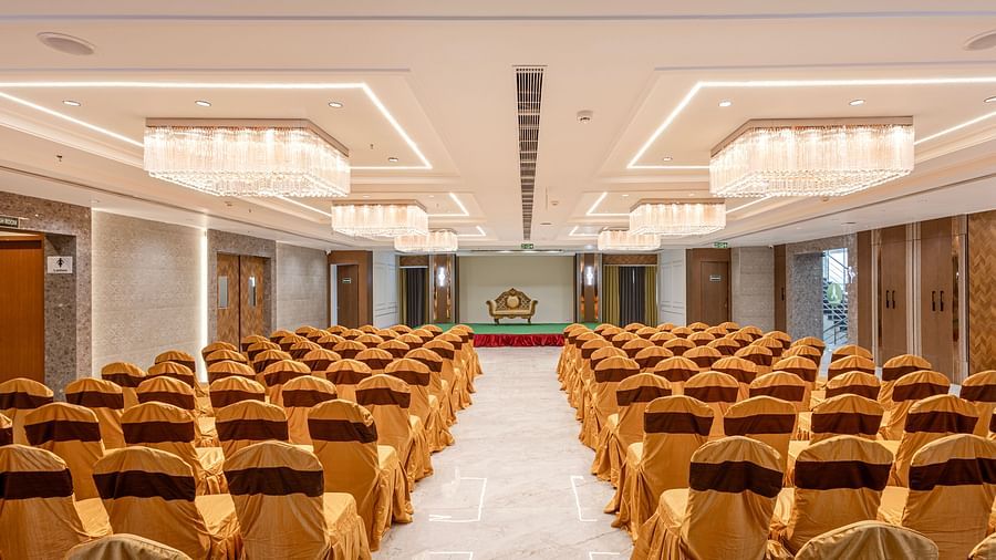 Central aisle view of a grand banquet hall with multiple chandeliers at Lemonridge Hotels, IDPL Balanagar.