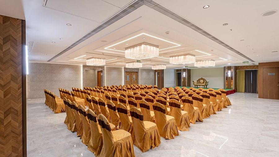 Grand conference hall set up with gold chair covers and chandeliers at Lemonridge Hotels, IDPL Balanagar.