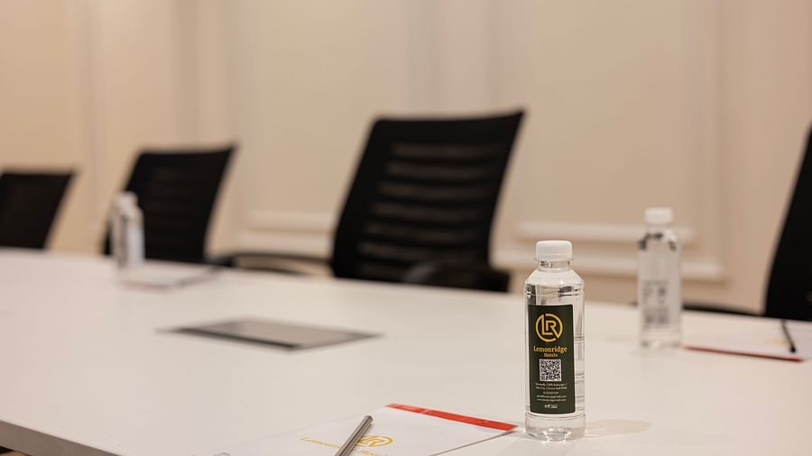 Close-up of boardroom table with bottled water and notepads at Lemonridge Hotels, IDPL Balanagar.
