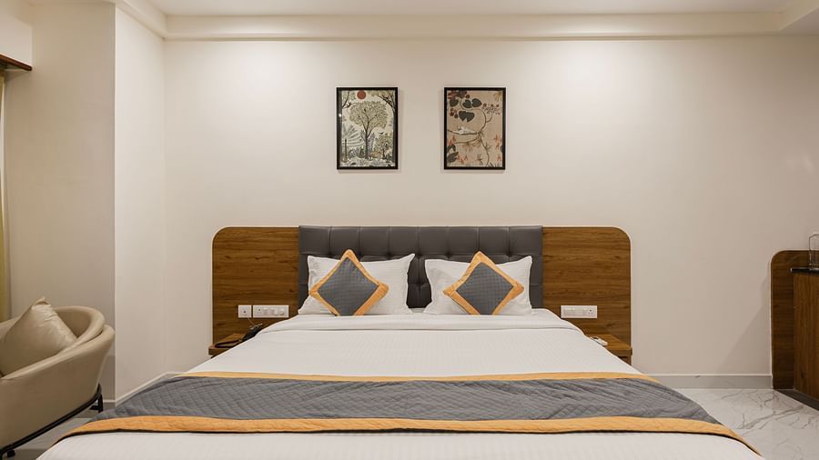 Front view of a neatly arranged king bed with cushions and clean white linen at Lemonridge Hotels, IDPL Balanagar.