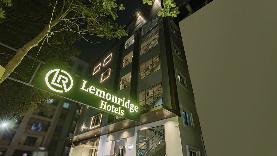 Night view of Lemonridge Hotels building signage surrounded by greenery at IDPL Balanagar.