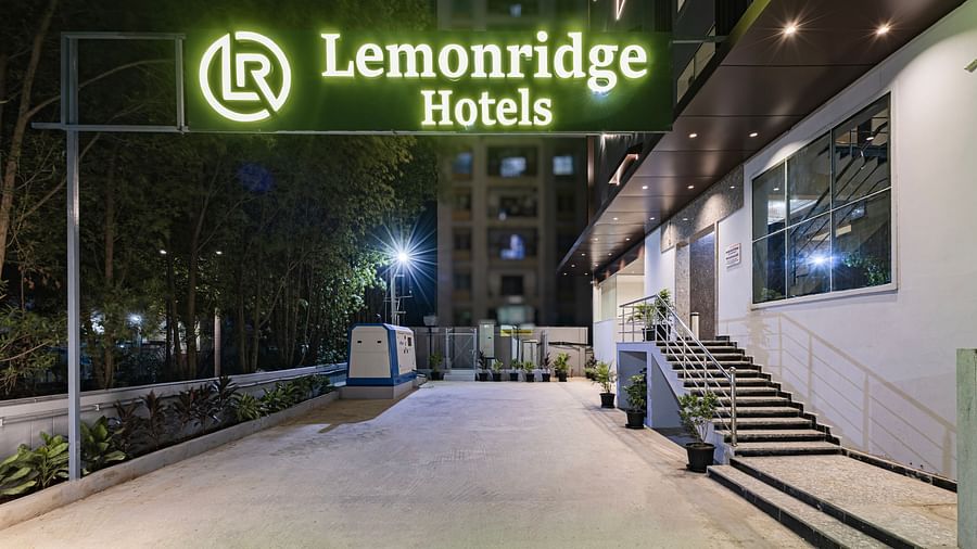 Night view of the entrance at Lemonridge Hotels, IDPL Balanagar, featuring the lit signboard and a wide, well-paved approach.