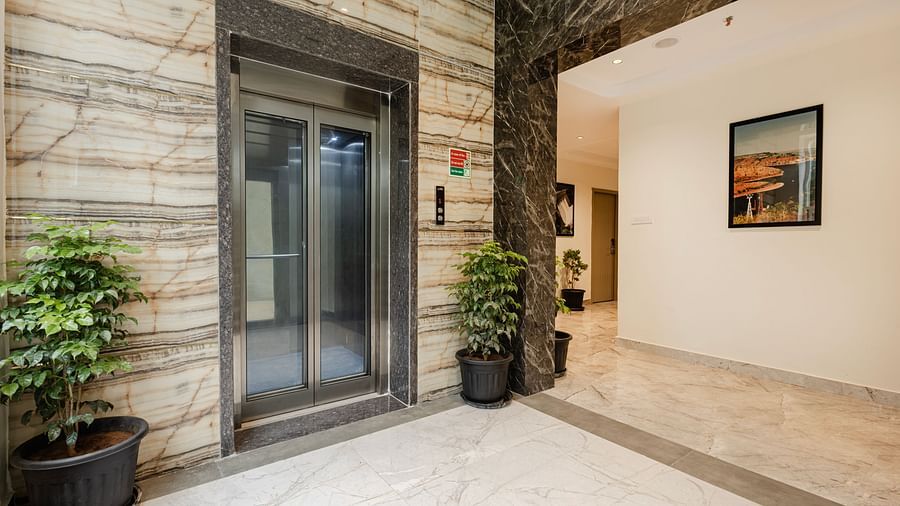 Lift lobby area with marble walls and indoor plants at Lemonridge Hotels, IDPL Balanagar.