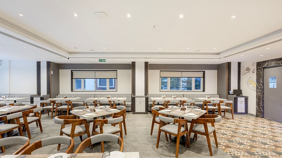 Modern restaurant dining setup with wooden chairs and white tabletops at Lemonridge Hotels, IDPL Balanagar.